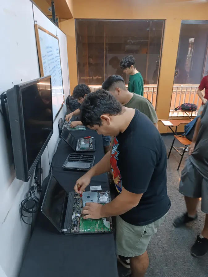 Estudiantes reparando notebooks en clase de Técnico en PC