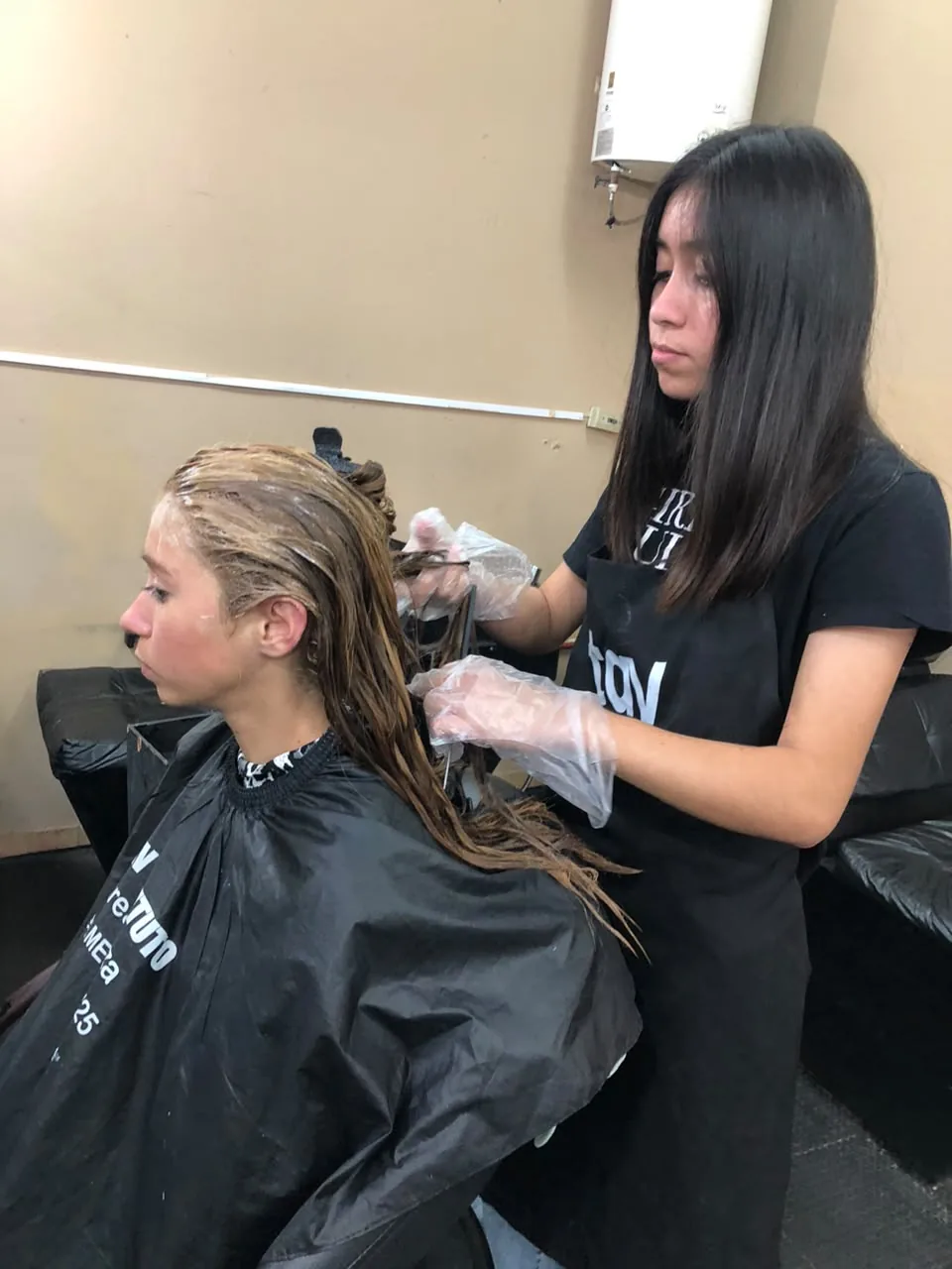 Alumna aplicando coloración capilar en taller de peluquería TAV
