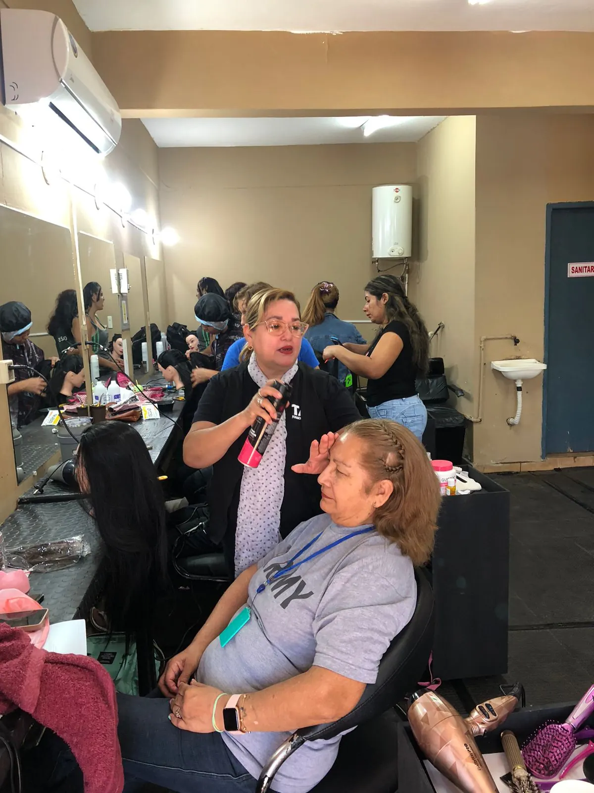 Instructora aplicando peinado y fijador en taller de peluquería TAV